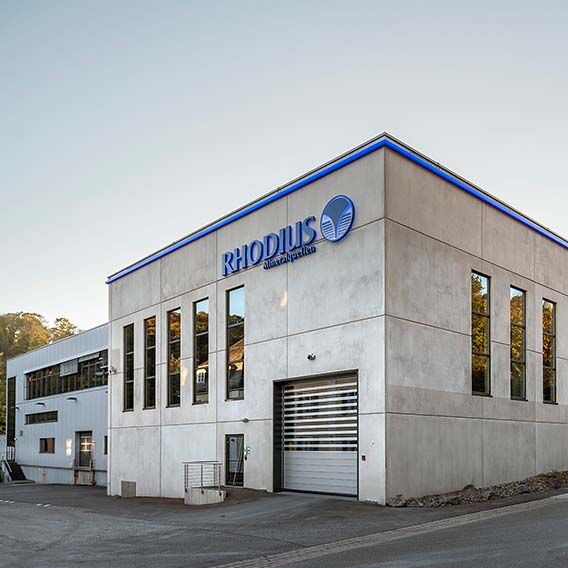 Exterior view of a white building with blue inscription RHODIUS.