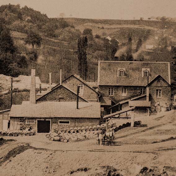 Bild in sepia, welches eine alte Ansicht der ersten Firmengebäude von RHODIUS zeigen.