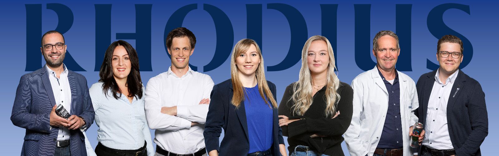 5 Männer und Frauen in unterschiedlicher Bekleidung stehen frontal zum Betrachter und lächeln.