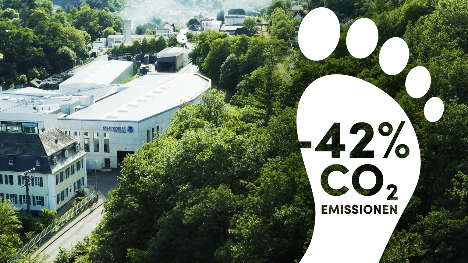 Wir legen sehr großen Wert auf Nachhaltigkeit. Ansicht auf das Firmengeländer von RHODIUS von oben. Am rechten Bildrand ist die Grafik von einem weißen Fußabdruck mit der Beschriftung –34% CO2 Emissionen eingefügt.